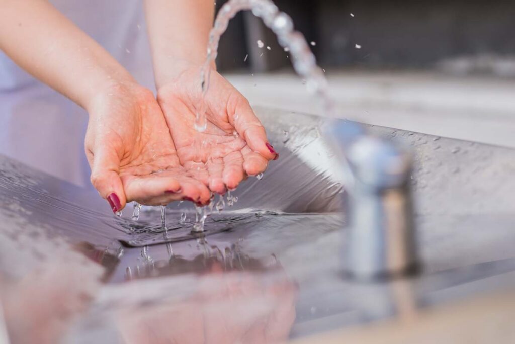 washing hands in faucet